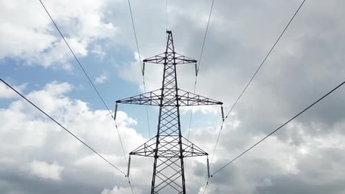 High Electricity Transmission Tower Standing Silhouetted Against Expansive Blue Sky Wispy White