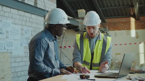 Two Construction Workers Collaborating on Building Project