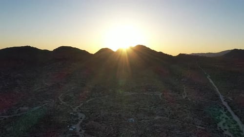 Bright Golden Sunset Over The Mountain With Desert Landscape In Foreground. - aerial