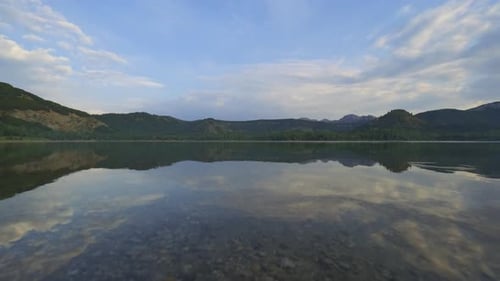 Beautiful clear lake surrounded by mountains. Summer scenery . Clear water with a reflection of c