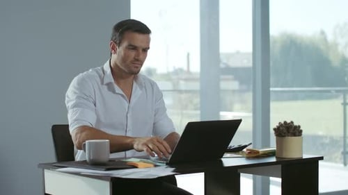 Man Working on Laptop at Desk Indoors Daytime