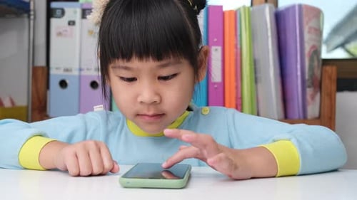 Young Girl Engaged with Smartphone at Table