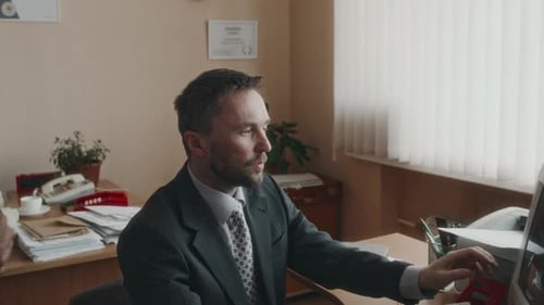 Erfahrener Angestellter, der einen Kollegen berät und an einem großen Retro-Monitor arbeitet