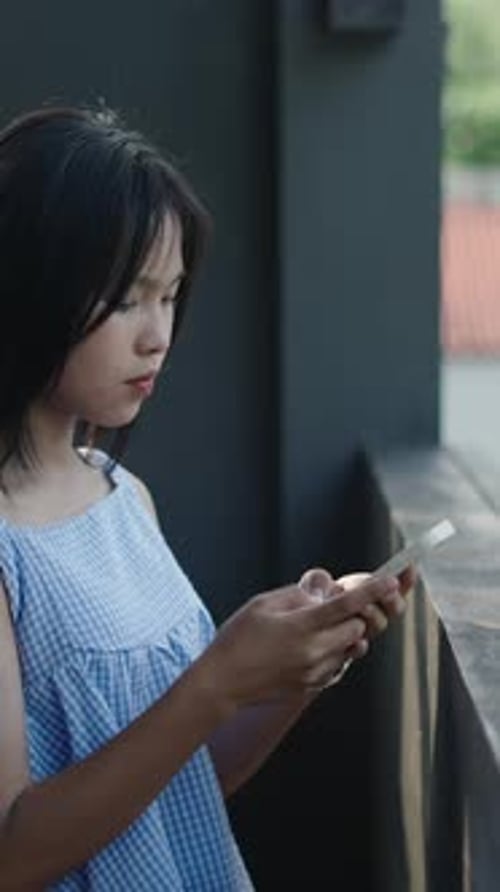 Slow Motion Young Asian Teenager Girl Consulting Her Smartphone on Wooden Terrace Happy Looking at