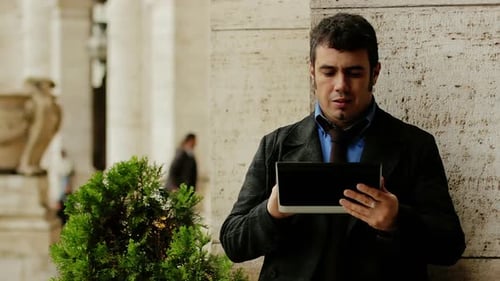Jeune homme d'affaires à l'extérieur du bureau utilisant une tablette
