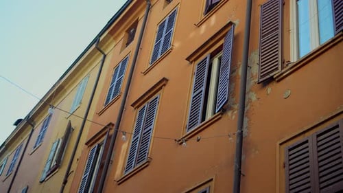 Eine leuchtend orangefarbene Wand mit bunten Fenstern und Fensterläden verleiht der Gegend Wärme und Charme