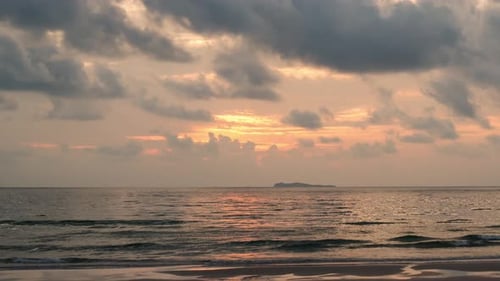 Timelapse of dramatic sunrise with orange sky in a cloudy day at the ocean.