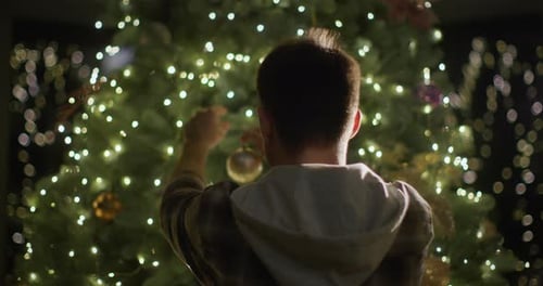 Person Decorating Christmas Tree with Ornament