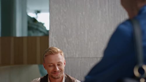 Hotel Concierge Checking Documents at Desk Closeup Smiling Man Meeting Guests