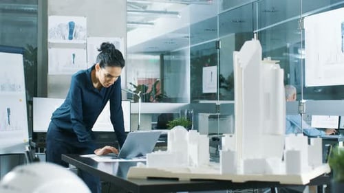 Female Architectural Designer Works on a Laptop, Engineering New Building Model for the Urban Plan