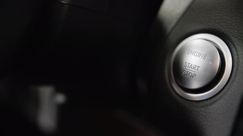 Close-up of pressing the engine start and stop button on a modern keyless vehicle.