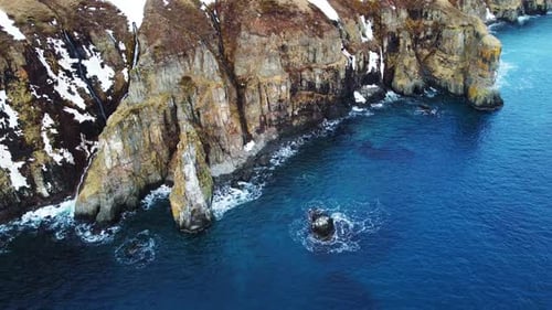 Flying Over Rocky Coastline Alongside Cliffside with Blue North Atlantic Ocean Water at Spring