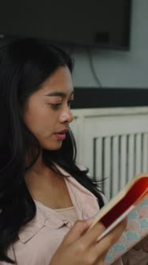 Young Woman Reading Book Indoors at Home