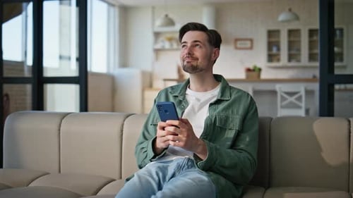 Young Man Using Smartphone on Couch at Home