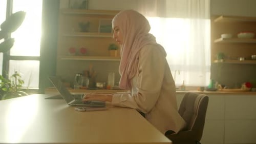 Muslim Business Woman Wearing Hijab Working on Laptop on Desk Table at Home Feel Tired Sunlight