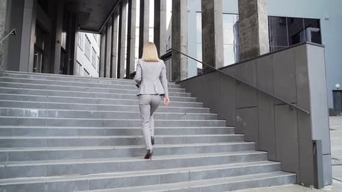 rear view Business woman employee climbs up stairs the step. To office center outside. Businesswoman
