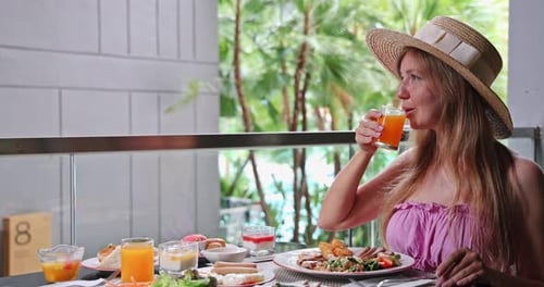Woman enjoying breakfast on tropical resort balcony - Luxury travel