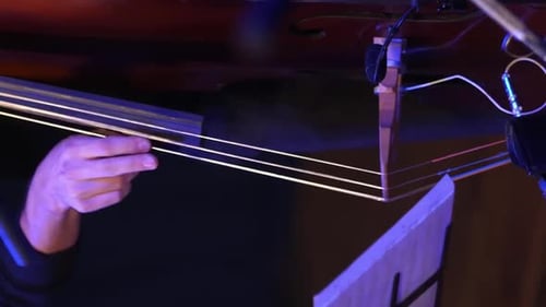 Man Playing a Double Bass in a Dark Room