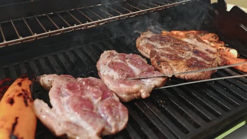 The Cook's Hands with Metal Tongs Carefully Place the Steak on a Wooden Board