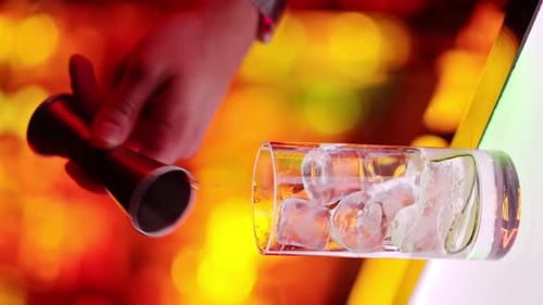 Barman making cocktails with whiskey liquor alcohol at the bar at night with red neon lights, slow m