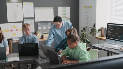 Teacher Assisting her Students During Programming Lesson in School