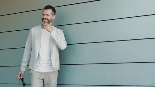 Man in Gray Blazer Stands Against Urban Wall