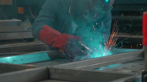 Man in mask works with welding metal structures at factory