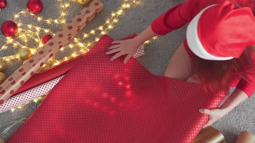 Woman Wrapping Christmas Gifts with Red Wrapping Paper