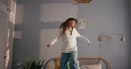 Cheerful Girl in Casual Listening to Rock and Dancing Energetic Cheerful Dance on the Bed at Home in