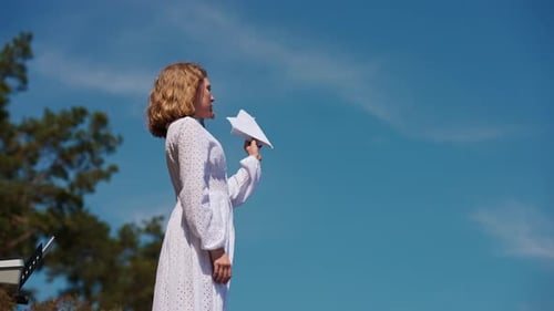 Young Adult Reads Paper on Stage Outdoors