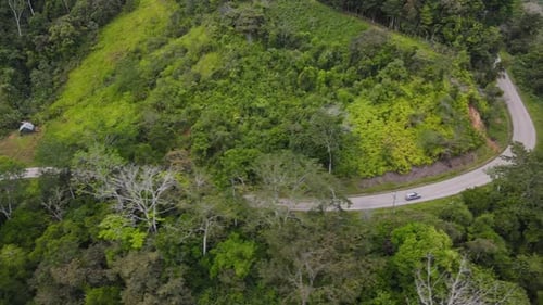 Aerial shot tracking a car driving on the road through the hills