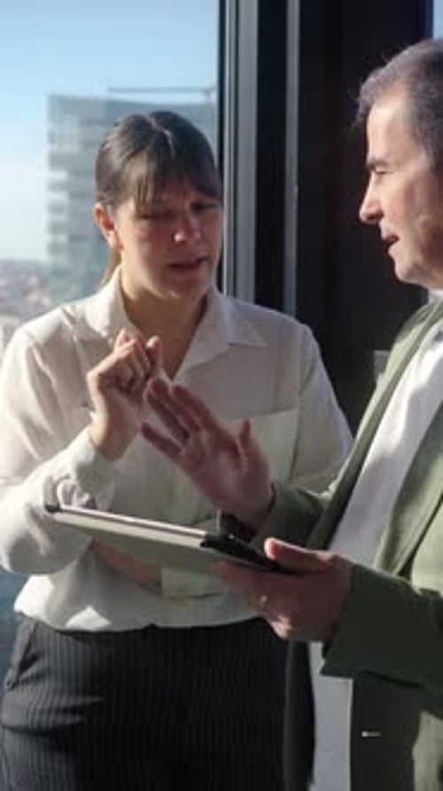 Businesspeople Discussing Strategy on Tablet in Modern Office