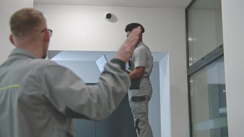 Multi Ethnic Installers Sets Up Security Camera in Office Hallway Using Laptop