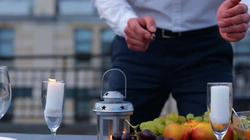 Man Lighting Candles on Rooftop Dinner Table