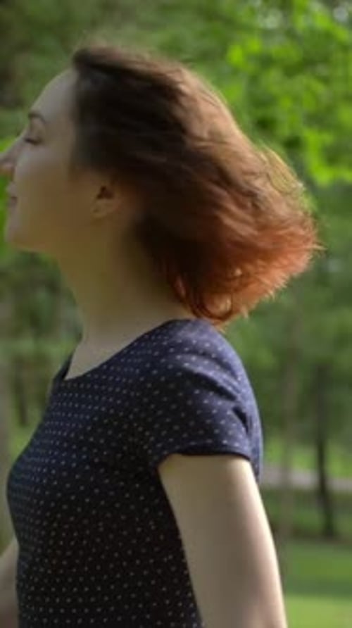 Vertical of Portrait of a Young Beautiful Girl Unfolding Into the Camera in the Park