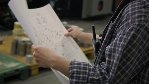 Un contremaître méconnaissable analysant un dessin d'assemblage détaillé