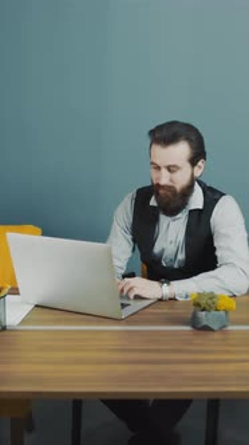 Man with Beard Working on Laptop at Desk Indoors