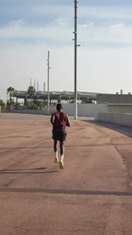 Man Runs on Paved Path in Urban Setting