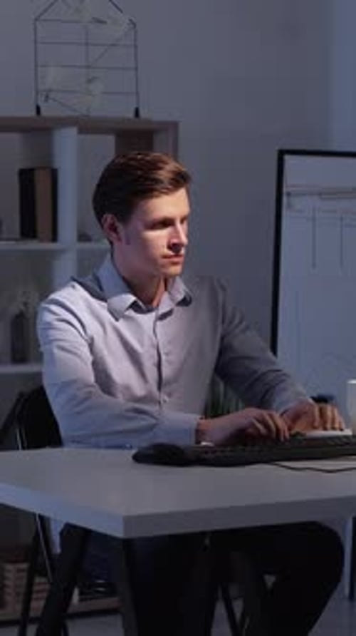 Young Adult Working at Computer in Office at Night