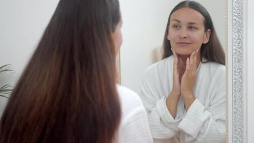 Woman Admiring Herself in Mirror Wearing White Robe