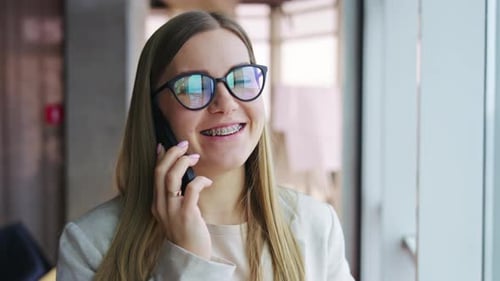 Smiling Woman Talking on Phone in Modern Office