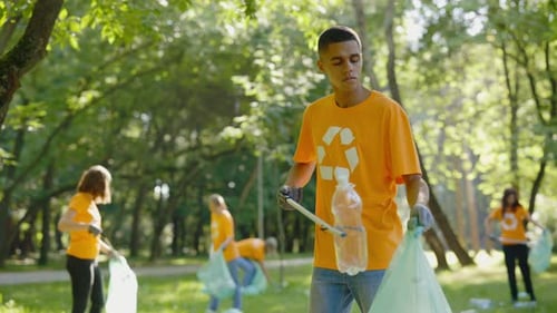 Multiethnic Man Using Trash Picker While Collecting Garbage in Bin Bag Group of Diverse Volunteers