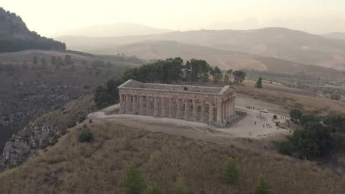 El templo de Segesta muestra columnas dóricas en la cima de una colina al atardecer con turistas