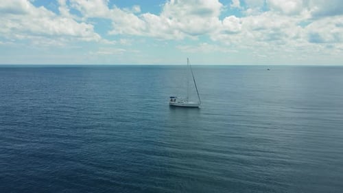 Sailboat Floating in the Middle of the Ocean on a Calm Day A Peaceful Scene of a Lone Sailboat