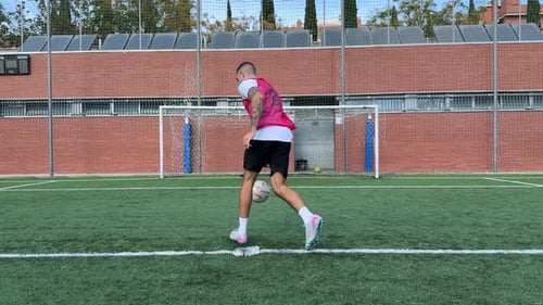 Man Kicks Soccer Ball at Goalie on Field