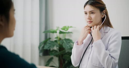 Friendly Doctor Examining Patient with Stethoscope in Clinic