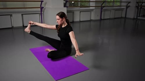 im Studio für spirituelle Entwicklung Meisterkurs in Yoga-Mädchen mit langen Haaren und schwarzem Trainingsanzug