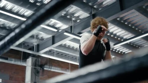 Aggressive Kickboxer Making Punches At Gym. Strict Sportsman Doing Hits On Ring. Ambitious Fighte...