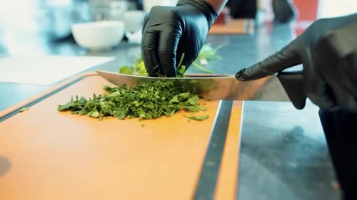 In a close-up shot, the chef skillfully chops parsley on a wooden cutting board.