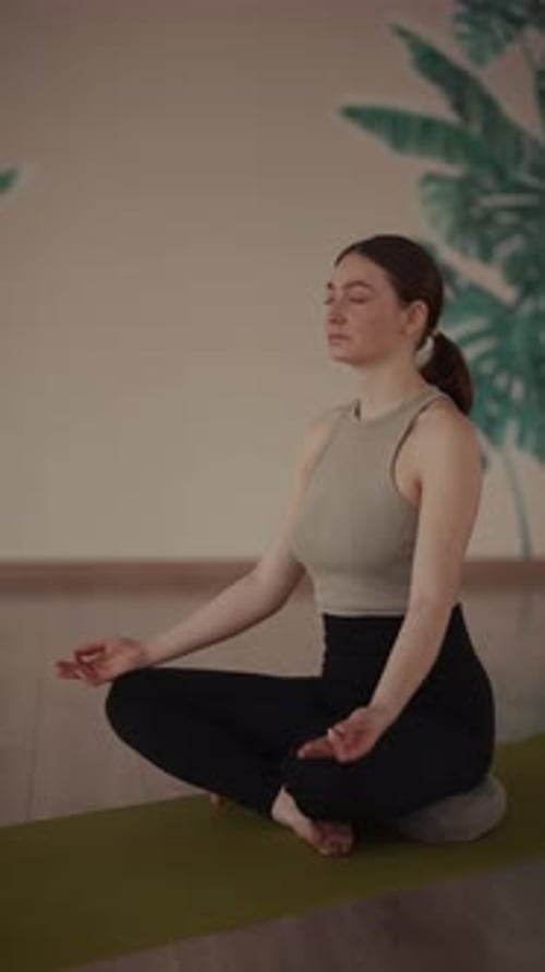 Woman meditating on yoga mat indoors